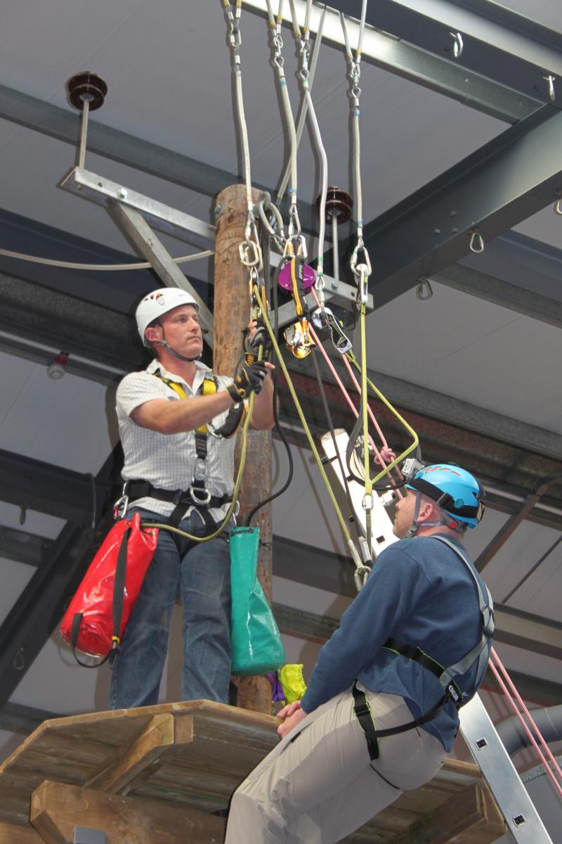 Two men demonstrating tree surgery harnesses and equipment 