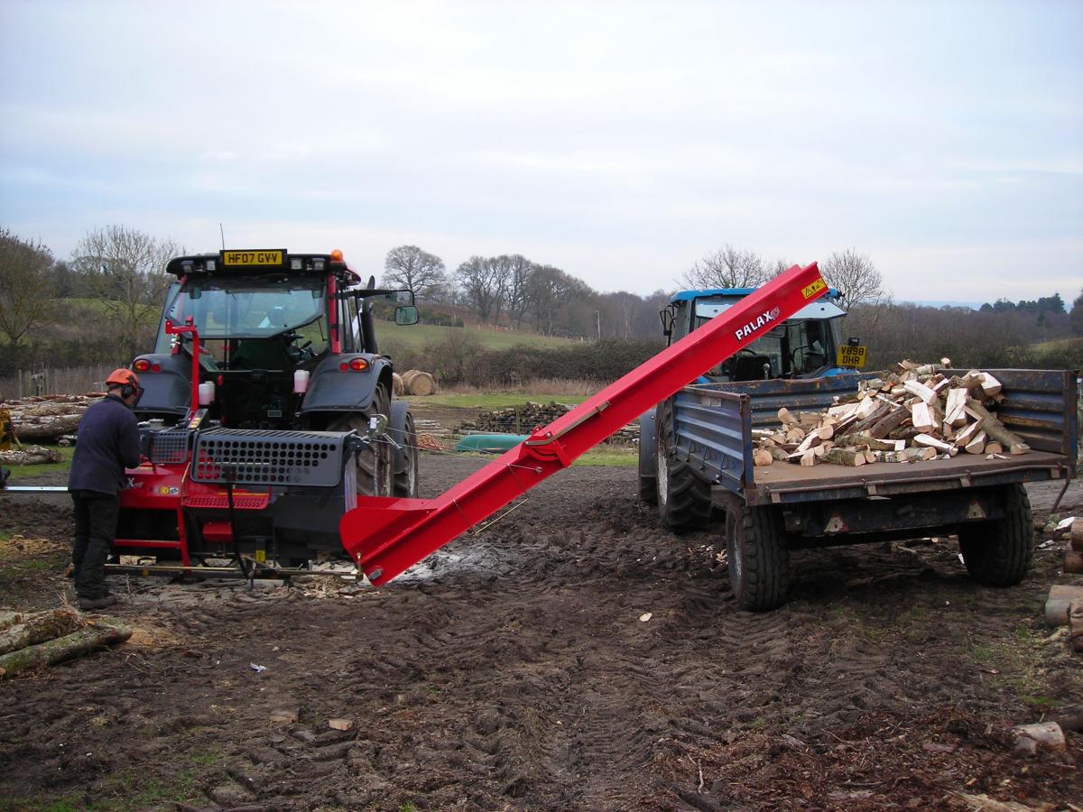 Wood splitting machine loading cut logs onto a tractor 