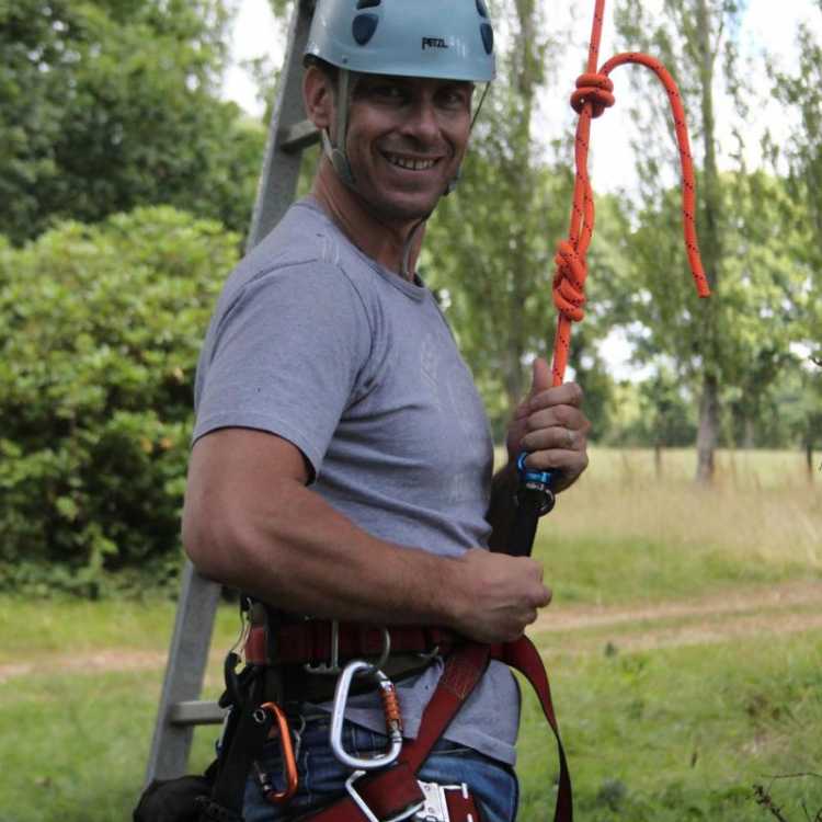 Man wearing his gear about to start tree climbing 